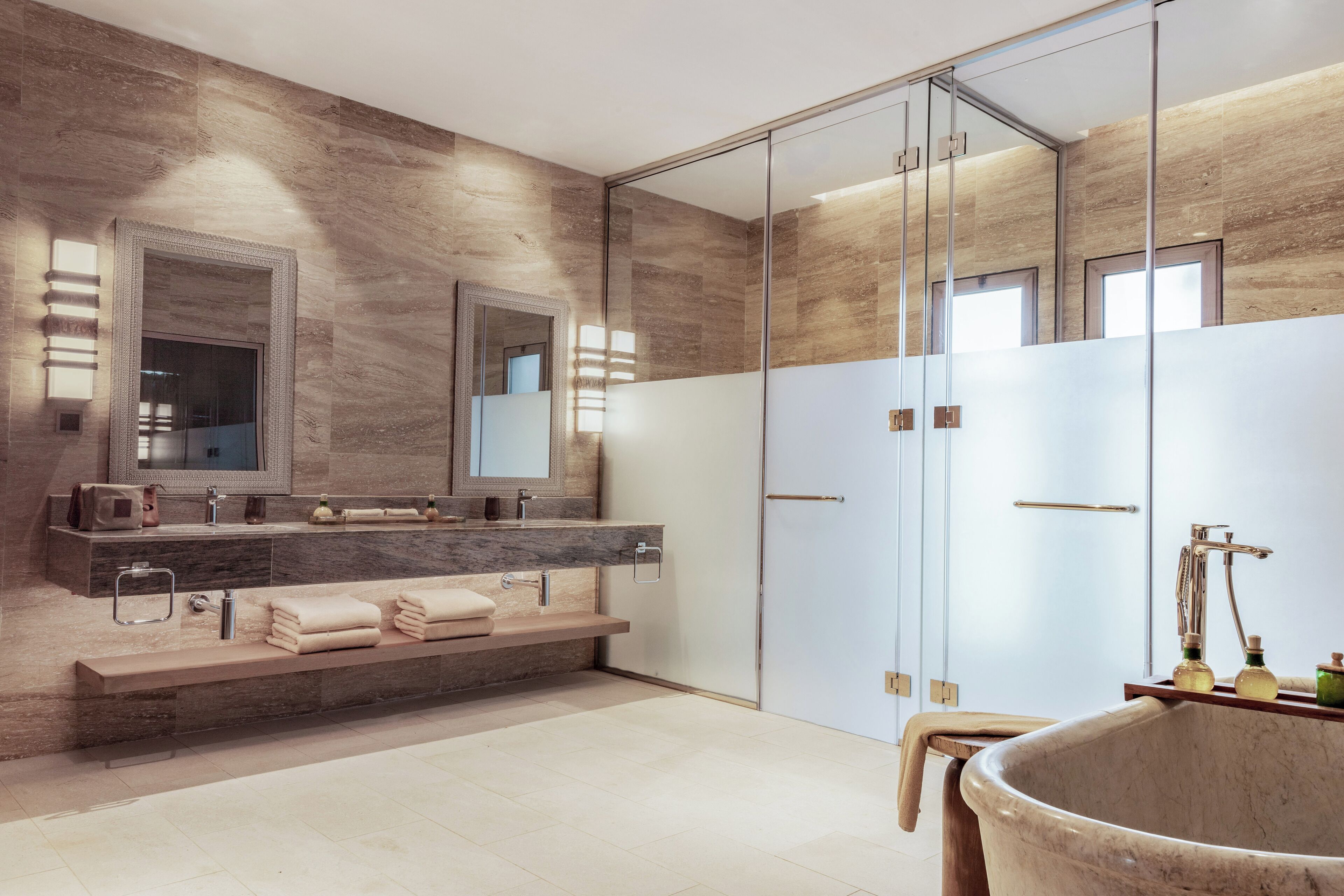 A modern bathroom with a marble vanity, a large mirror, and a freestanding bathtub.