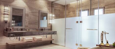 A modern bathroom with a marble vanity, a large mirror, and a freestanding bathtub.