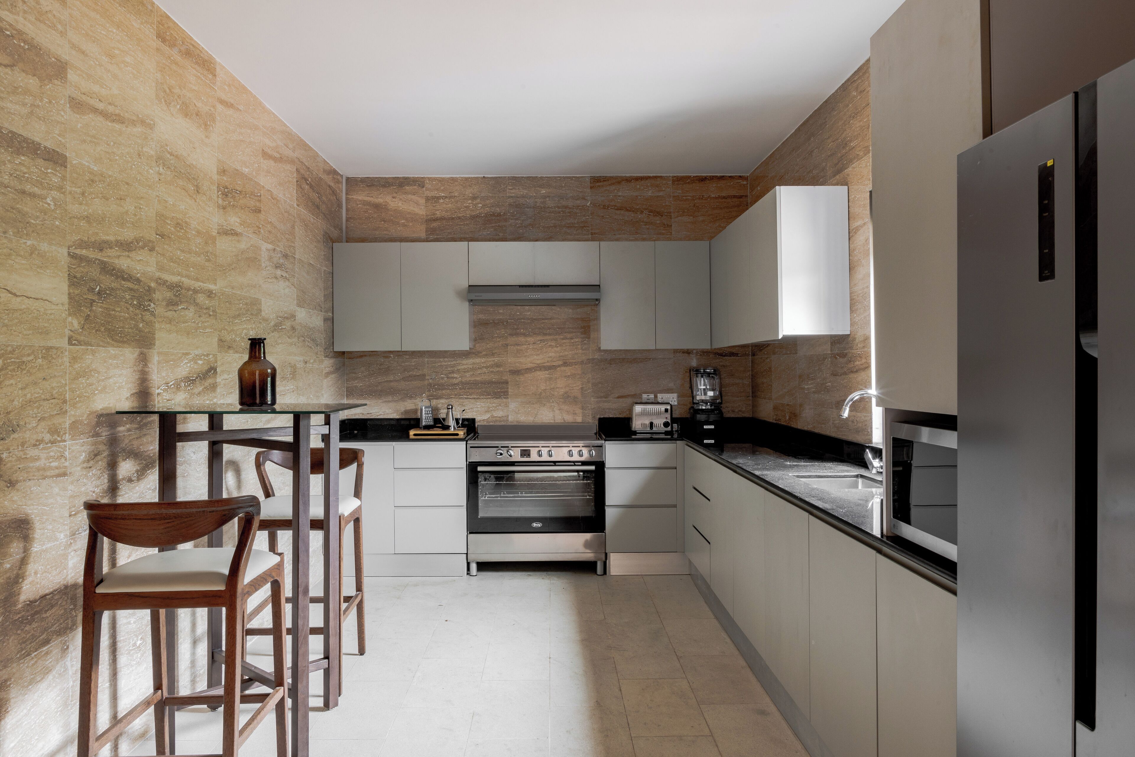 A modern kitchen with a built-in oven, a coffee machine, and a refrigerator.