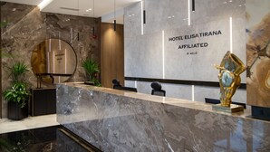 Un área de recepción de hotel moderna, con un mostrador de mármol, un amplio mostrador de madera y un cartel en la pared.