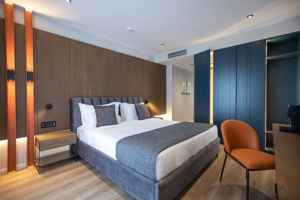 A modern hotel room with a large bed, a desk, and a chair.