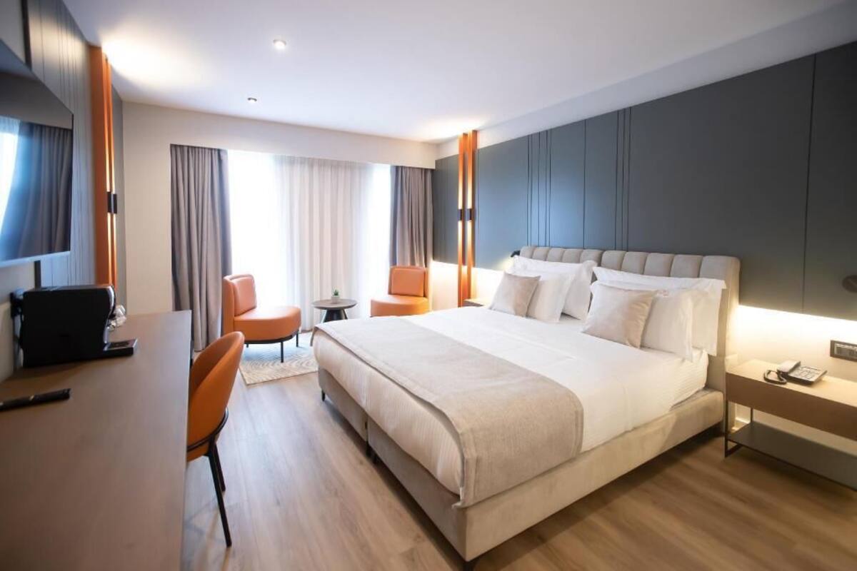A hotel room with a large bed, a desk, a chair, and a small table.