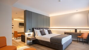 Una habitación de hotel moderna con una cama grande, dos sillas, un escritorio y un televisor de pantalla plana.