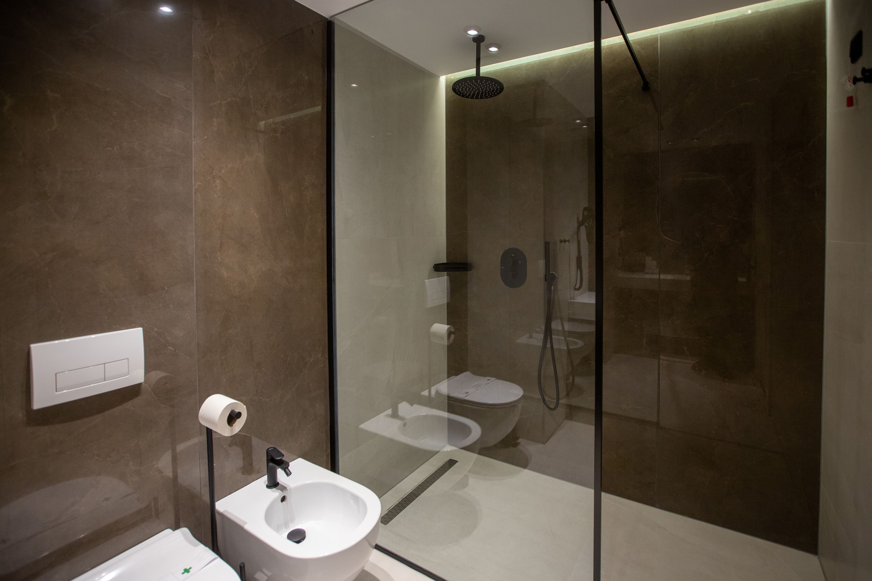 A modern bathroom with a glass-enclosed shower, a white sink, and a toilet.