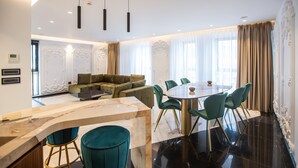 Un área de comedor moderna con encimera de mármol, sillas tapizadas en verde y una mesa redonda.