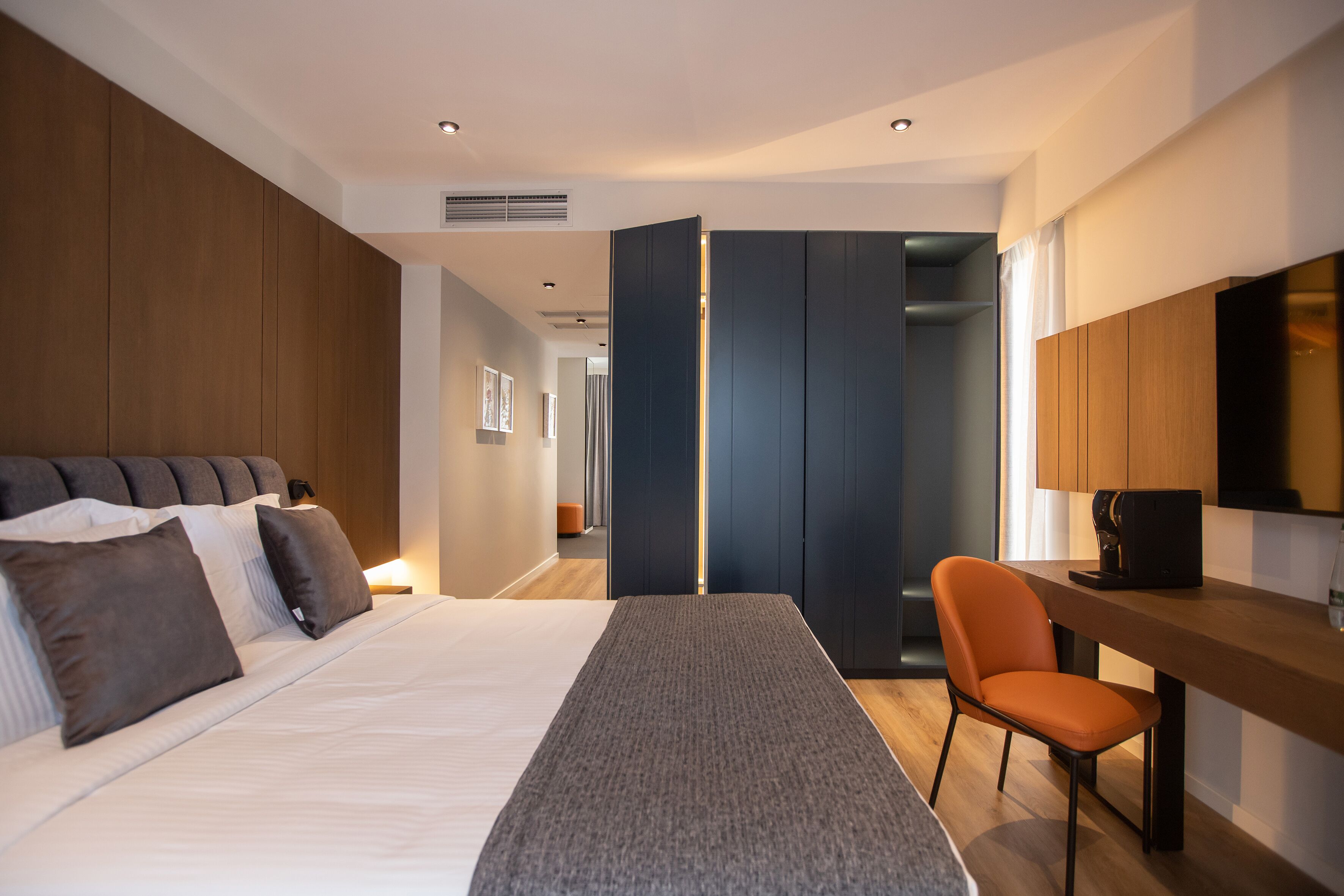 A modern hotel room with a large bed, a desk, and a chair.