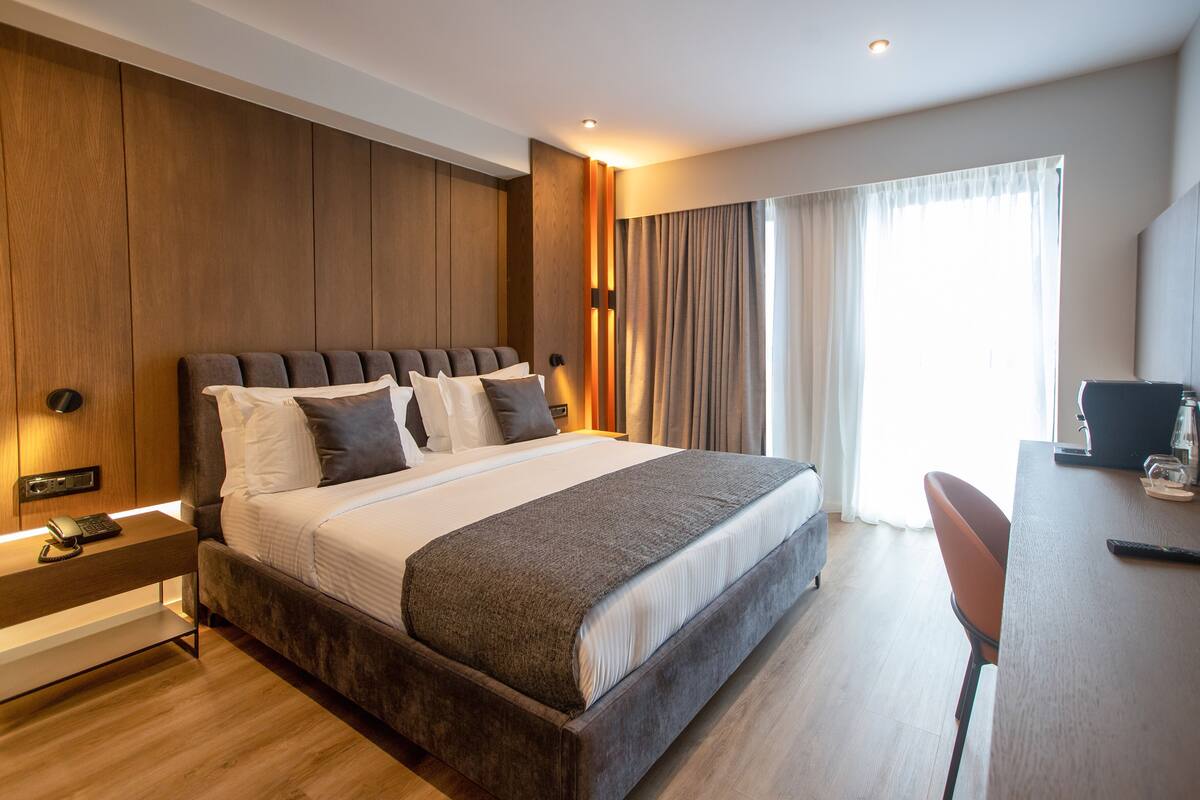 A modern hotel room with a large bed, a desk, and a chair.