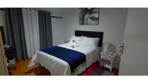 Et hotelværelse med seng, natbord, skrivebord og stol.