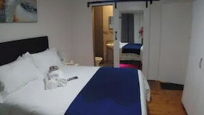 Et hotelværelse med en seng, et natbord og en dør til et badeværelse.