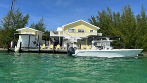 A waterfront property with a large house, docked boat, and outdoor seating area. - Bimini Vacation Apartment - APT#3 (Bimini)