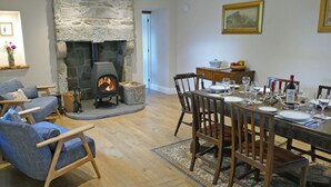 A cozy living room with a stone fireplace, a dining area set for a meal, and a comfortable seating area with a sofa and chairs. - 4 bedroom accommodation in Advie, near Grantown-on-Spey (Advie, near Grantown-on-Spey)
