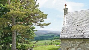 A stone building with a sloped roof, surrounded by a grassy area and trees. - 4 bedroom accommodation in Advie, near Grantown-on-Spey (Advie, near Grantown-on-Spey)
