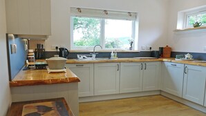 A kitchen with white cabinets, a wooden countertop, a window with a view of greenery, and a wooden floor. - 4 bedroom accommodation in Advie, near Grantown-on-Spey (Advie, near Grantown-on-Spey)