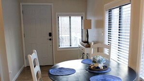 A dining area with a round table, white chairs, and blue placemats. - A-Frame Mountain Retreat (Gerrardstown)