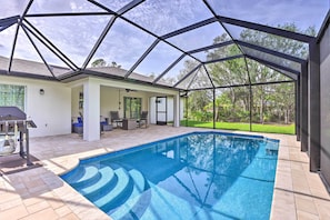 A covered swimming pool with a geometric roof structure, a patio area with outdoor furniture, and a view of a green landscape. - Private Heated Pool, Near Warm Mineral Springs (North Port)