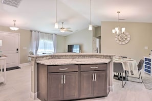 A modern kitchen with granite countertops, dark cabinetry, and pendant lighting. - Private Heated Pool, Near Warm Mineral Springs (North Port)