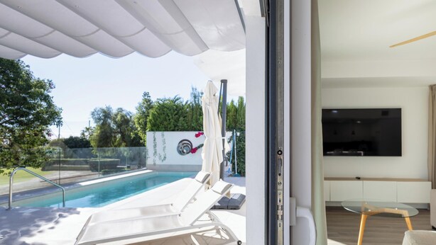 A modern outdoor pool area with a glass door leading to a living room with a flat-screen TV. - Ref. 400719 (Motril)