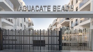 A gated entrance to a residential building named "Aquacate Beach" with a modern design and balconies. - Ref. 400719 (Motril)