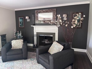 Una sala de estar con dos sillones, una chimenea y decoración en las paredes.