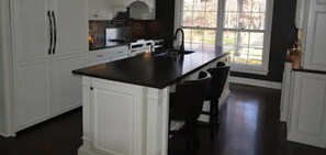 A kitchen with white cabinetry, a dark countertop island, and a window providing natural light.