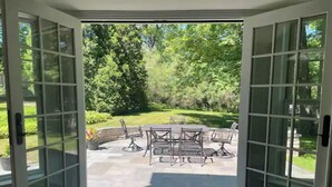 Eine Terrasse mit Tisch und Stühlen, umgeben von Steinplatten und Grünpflanzen.