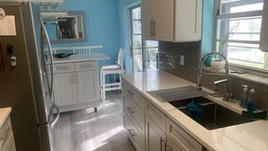 Una cocina moderna con armarios blancos, un refrigerador de acero inoxidable y un ventanal con vista a follaje.