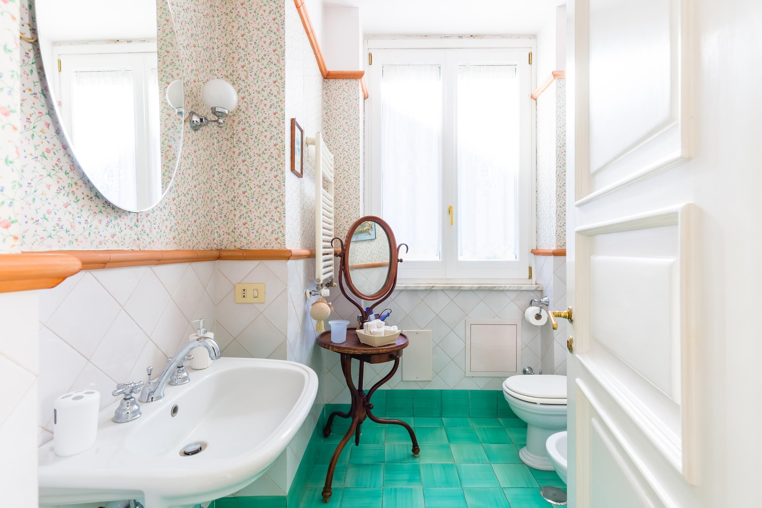 Ein Badezimmer mit Waschbecken, Spiegel, Toilette und einem Fenster.