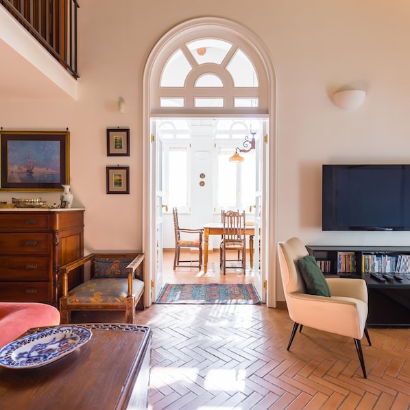 Cozy living space with a high ceiling, arched doorway, and comfortable seating area.