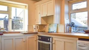 Una cucina con mobili bianchi, un fornello, un forno e una lavatrice.