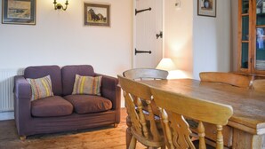 Un accogliente soggiorno con un tavolo da pranzo in legno, un divano con cuscini colorati e una sedia di legno.
