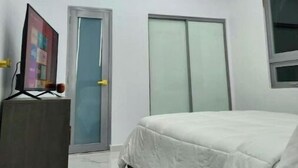 Un dormitorio moderno con cama, escritorio, puerta y armario.
