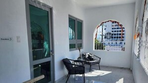 Una habitación limpia y moderna con puerta de vidrio, una mesita con sillas y un ventanal con vistas a edificios.