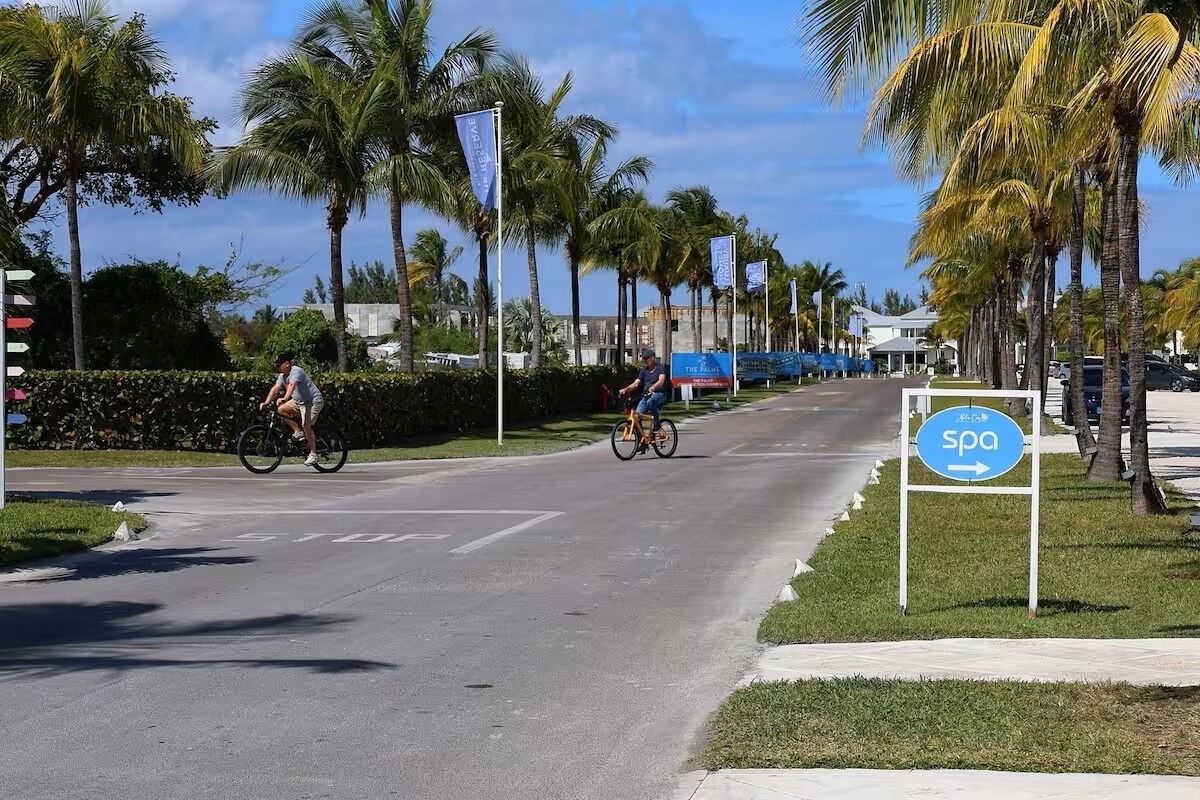 A street with cyclists, palm trees, and a spa sign.