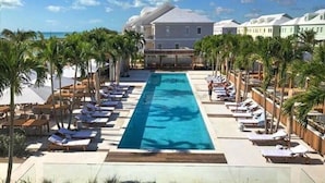 Ein Resort mit einem zentral gelegenen Pool, Liegestühlen und Palmen.
