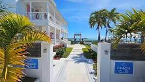 Ein Weg zu einem Beachclub mit Palmen und Blick auf den Ozean.