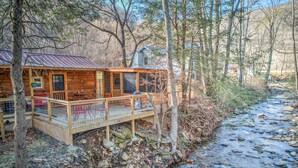 Une cabane rustique dotée d’une terrasse en bois, d’un toit en métal et d’un petit porche.