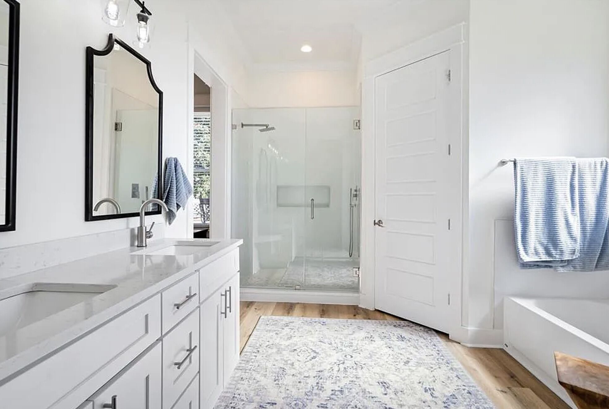 A modern bathroom with a glass shower enclosure, a white sink, and a large mirror.