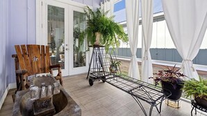 A covered porch with a wooden chair, a metal bench, and potted plants. - home in fort payne (Fort Payne)