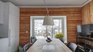 Eine moderne Küche mit Holzvertäfelung, einem großen Esstisch und einem Fernseher auf einem Holzgestell.