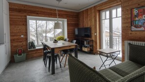 Eine moderne Küche mit Holzwänden, einem Esstisch, Stühlen und einem Fernseher.
