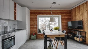 Eine moderne Küche mit weißen Schränken, einem eingebauten Backofen und einem Essbereich mit einem Holztisch und Stühlen.