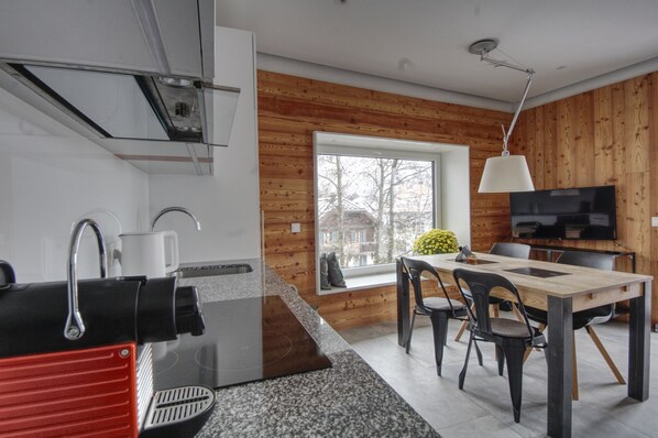 Une cuisine moderne avec un plan de travail en granit, un appareil électroménager rouge et une fenêtre donnant sur un paysage enneigé.