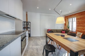 Une cuisine moderne dotée de plans de travail en granit, d’un four encastré et d’un coin repas avec une table et des chaises en bois.