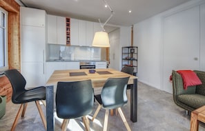 Une cuisine moderne avec des meubles blancs, une table à manger en bois et des chaises noires.