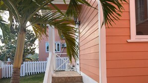 A pink house with a white picket fence, a stone staircase, and a palm tree. - Cute, clean and cozy cottage. 5 minute drive from Junkanoo beach and Bay street. (Nassau)