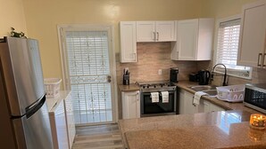 A kitchen with white cabinets, a stainless steel refrigerator, a gas stove, and a microwave. - Cute, clean and cozy cottage. 5 minute drive from Junkanoo beach and Bay street. (Nassau)