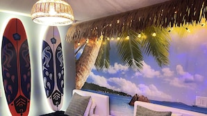Una stanza con un letto, un comodino e un murale raffigurante una spiaggia.