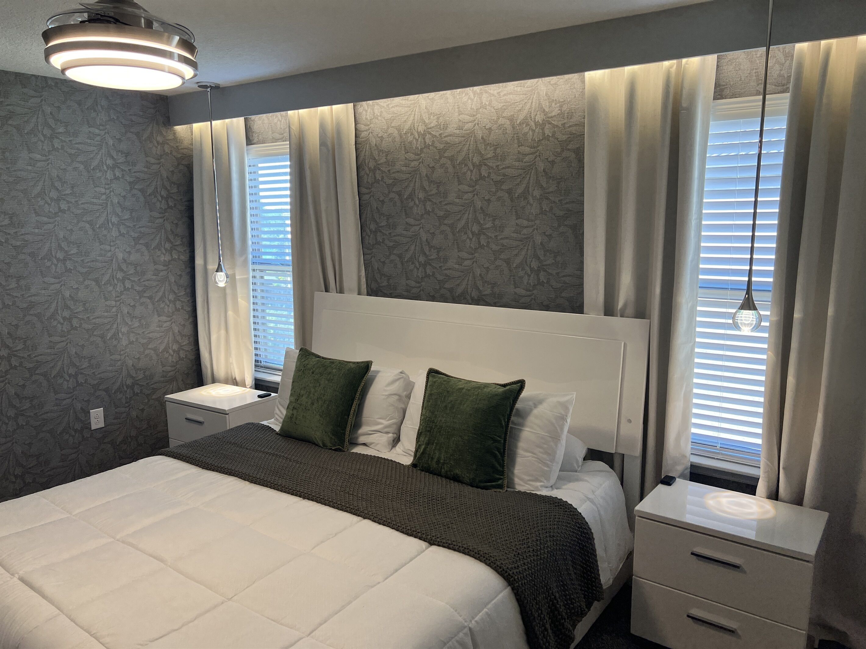 A bedroom with a bed, nightstands, a bedside table, and a window with curtains.