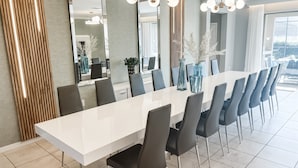 Un'area pranzo moderna con un tavolo bianco allungato, sedie scure e vasi decorativi.