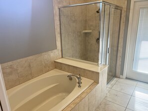 A bathroom with a bathtub, a glass-enclosed shower, and a mirror above the sink.
